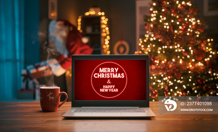 Christmas wishes on a laptop and Santa bringing gifts at home