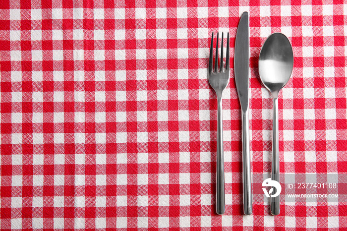 Table setting with silver cutlery on checkerboard napkin