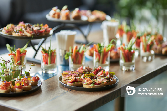 Lots of good food on the table. Small sandwiches on a black plate. Catering