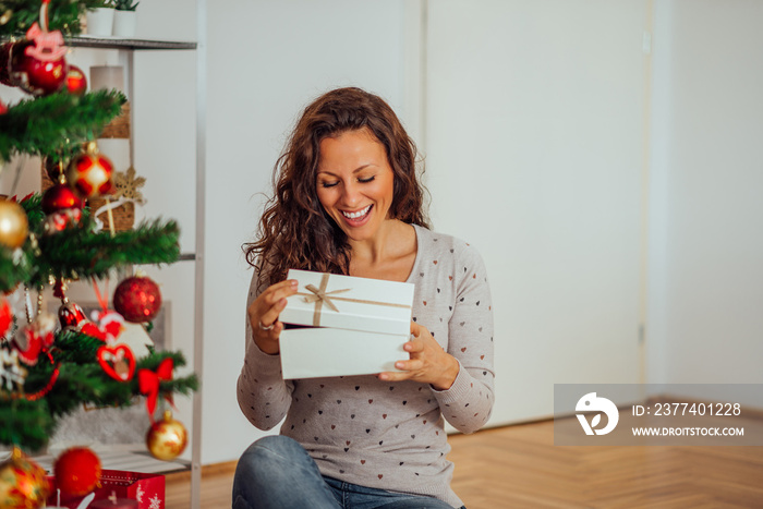 Happy Holidays! Woman opening Christmas gift box, portrait.