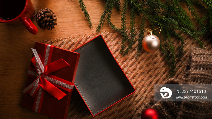 Open gift box on wooden background with Christmas decorations.