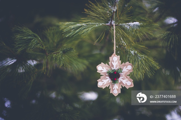 Closeup of a snowflake-shaped ornament on the Christmas tree in winter