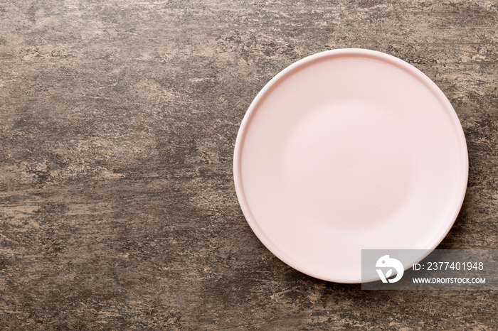 Top view of empty pink plate on cement background. Empty space for your design