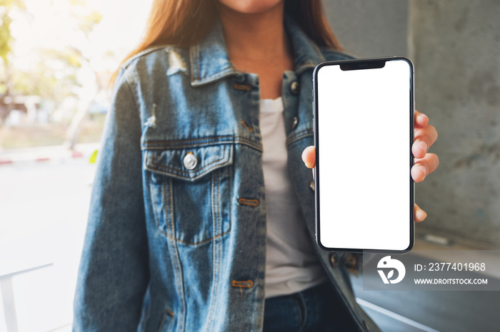 Mockup image of a woman holding and showing black mobile phone with blank screen in cafe