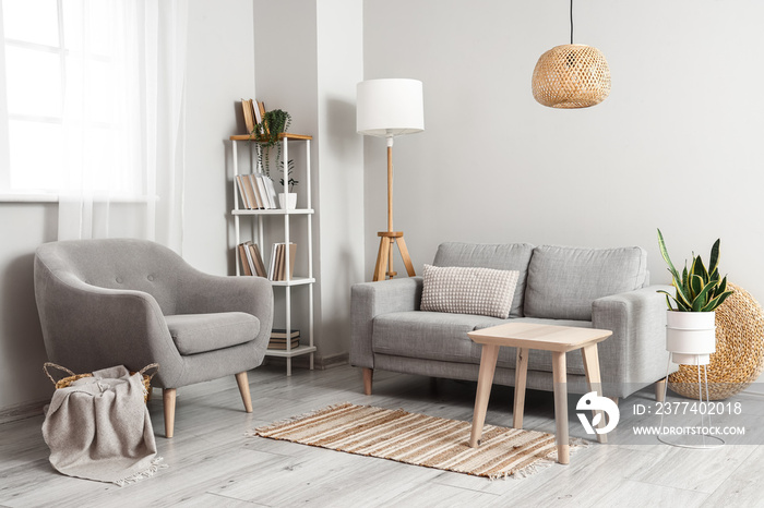 Stylish interior of light room with sofa, armchair and wooden table