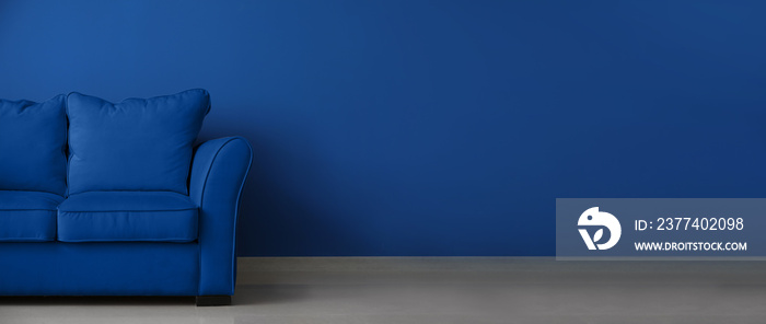 Stylish blue sofa near color wall