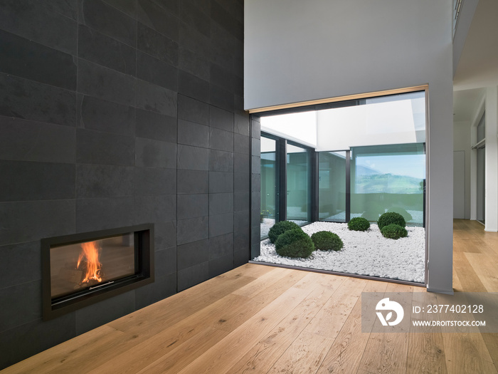 interiors shots of a modern empty living room with fireplace and hardwood floor overlooking on the j