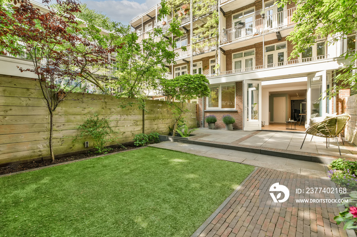 a backyard area with green grass and brick walkway leading to the front door, surrounded by lush tre