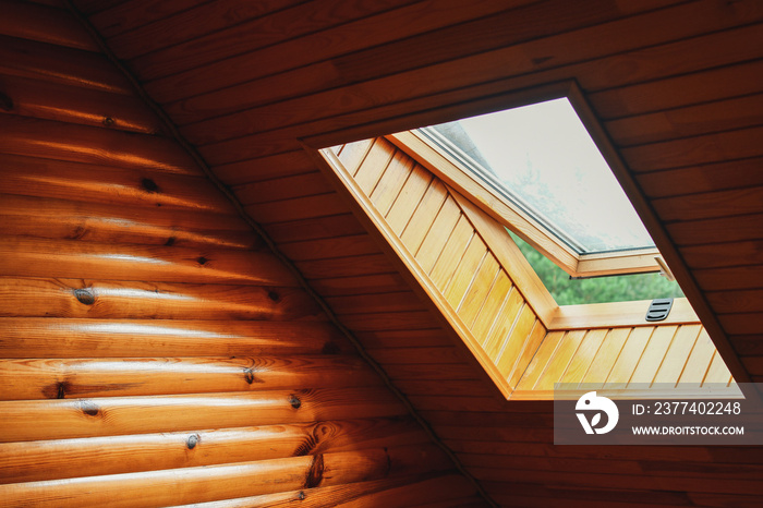 Detail of partially opened skylight window installed into roof of the wooden log house