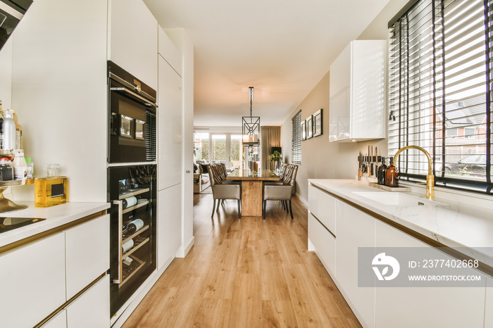 a kitchen with wood flooring and white cabinets in the middle of the room, there is a large window t