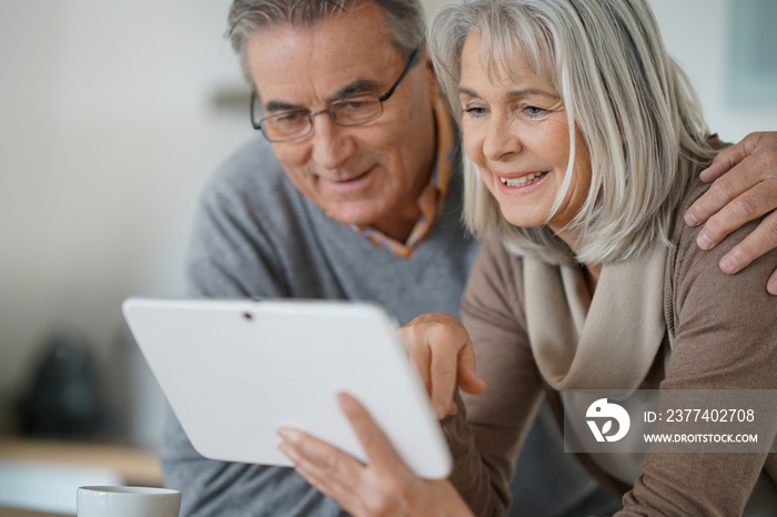 Senior couple at home using digital tablet