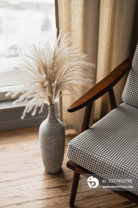 Mid-century retro chair and pampas grass bouquet in clay pot against window with curtains. Modern ae