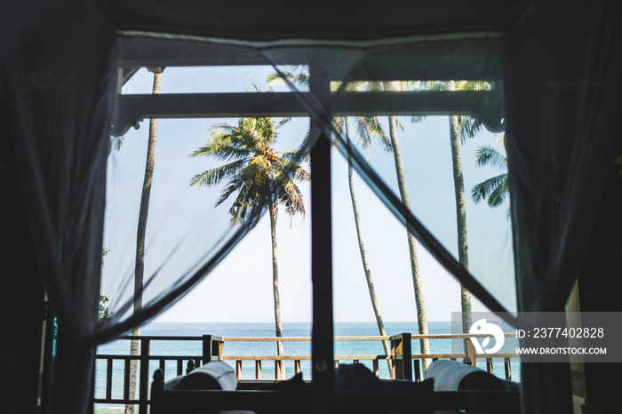 Tropical ocean and palm tree view through villa window in Bali. Leisure and vacations concept.