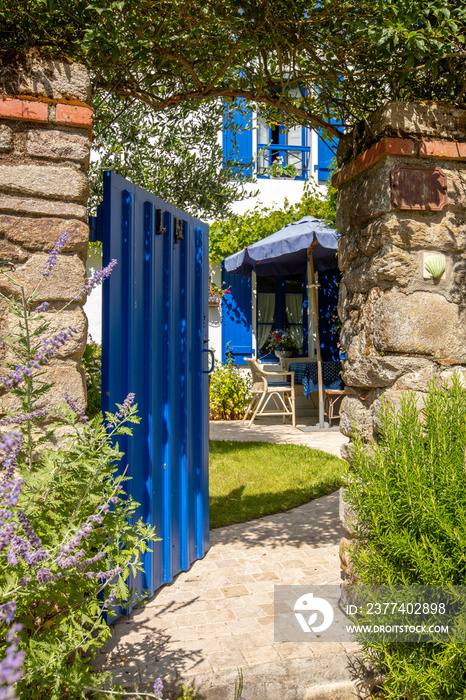 Porte ouverte sur un petit jardin fleuri.