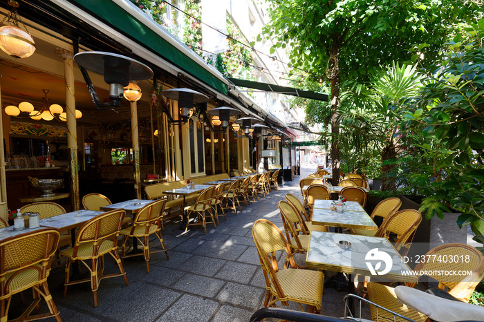 Cosy street with round tables and bright chairs of traditional outdoor French cafe in Paris