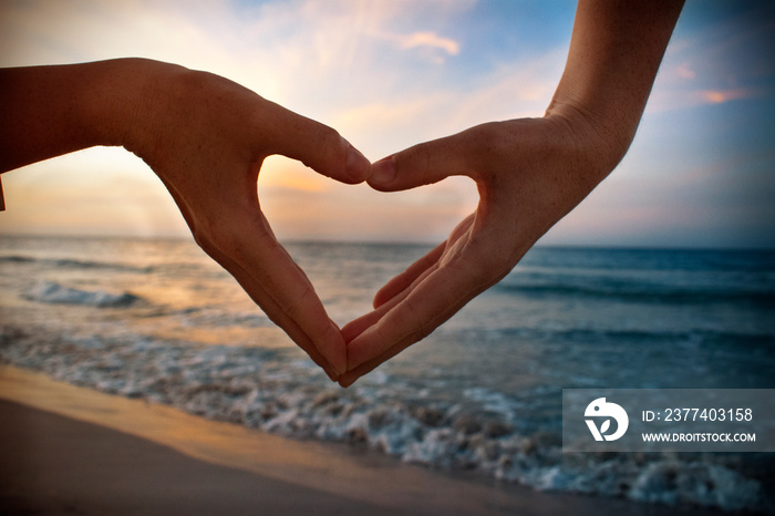 heart in hands on beach at sunset