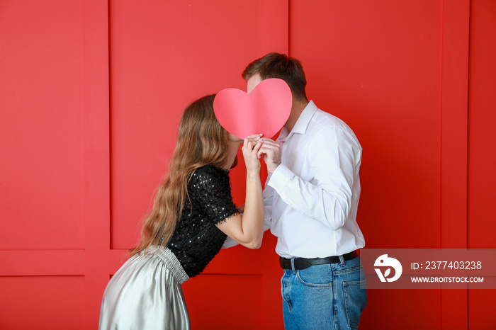 Happy young couple with red heart on color background. Valentines Day celebration