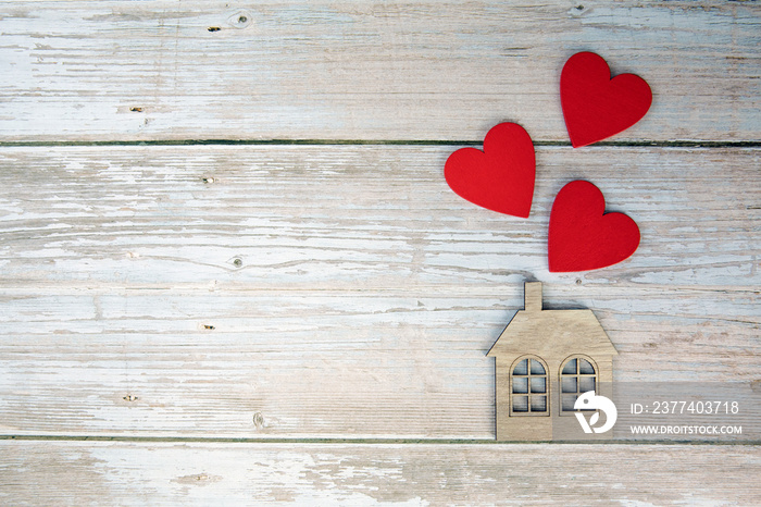 Wooden house with three red hearts on a wooden background. Love nest, love relationships. Buying a h