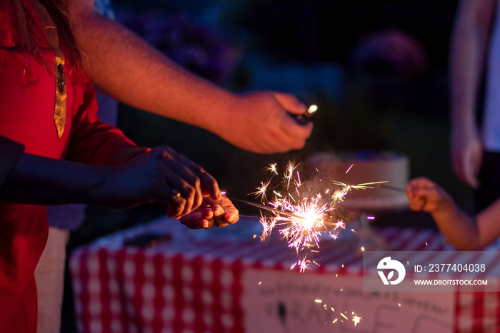 Closeup of a womans hand lighting sparklers in the backyard at a family celebration