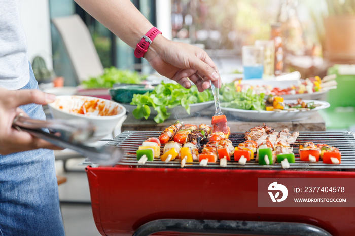 A man grilling pork and barbecue in dinner party. Food, people and family time concept.