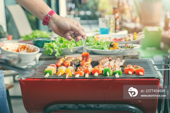 A man grilling pork and barbecue in dinner party. Food, people and family time concept.