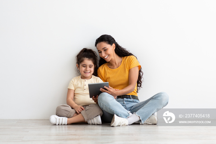 Happy Middle Eastern Mom And Little Daughter Using Digital Tablet At Home