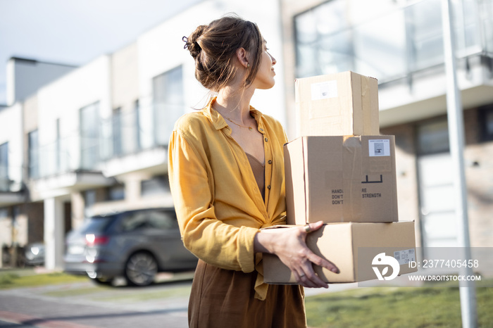 Woman holding parcels on the street in front of the house. Received the ordered goods at the post of