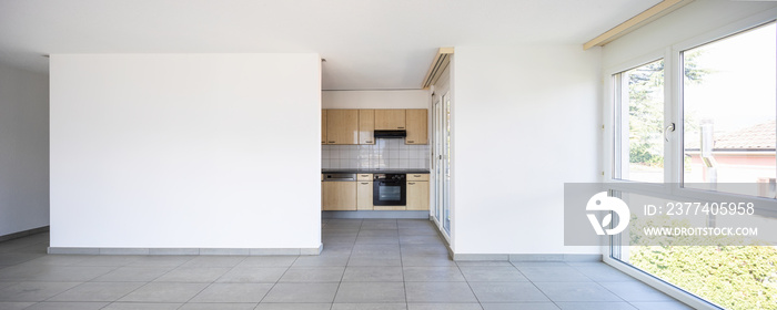 Empty room with windows and wooden kitchen