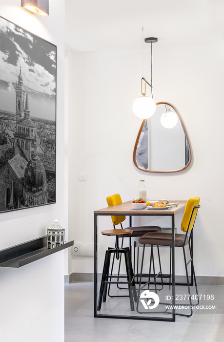 Lunch area of a modern apartment with a minimal wooden tall table with breakfast,stoods, modern lamp