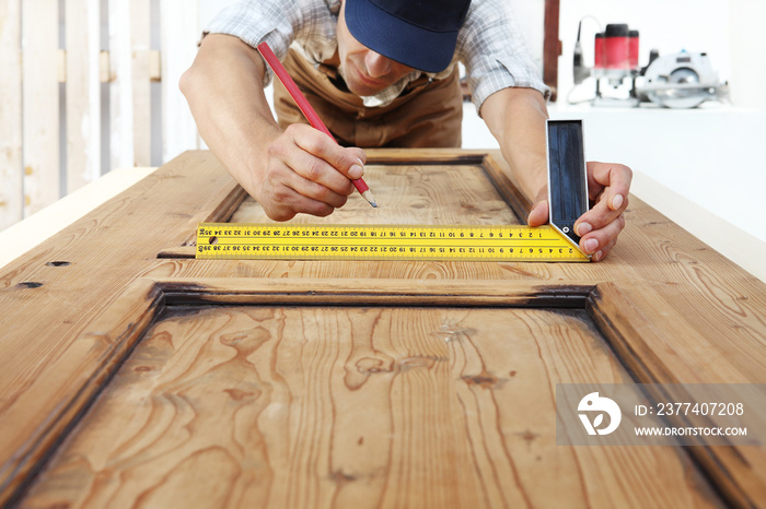 carpenter at work measures with the setsquare and pencil on wooden board background