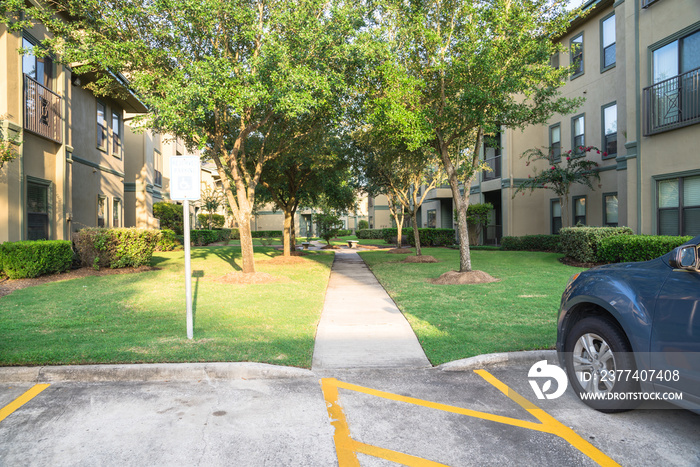 Clean lawn and tidy oak trees along the walk path through the typical apartment complex building in 