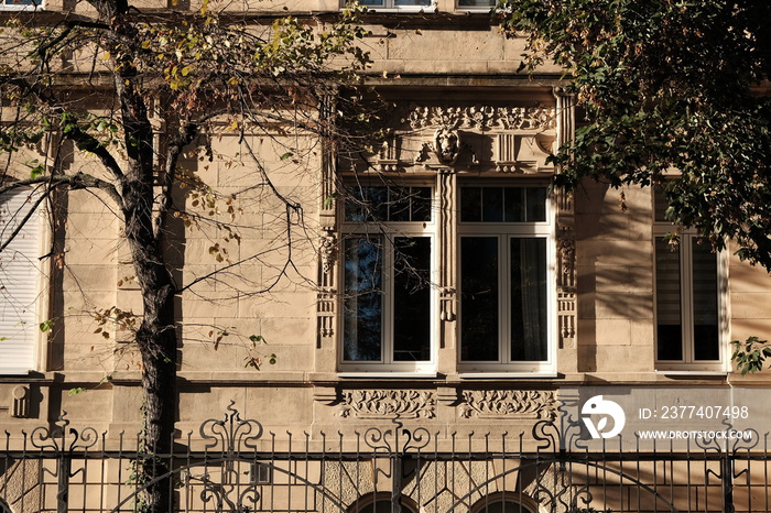 Fassade einer schön verzierten Villa aus Sandstein in Beige und Naturfarben mit altem Zaun aus Schmi