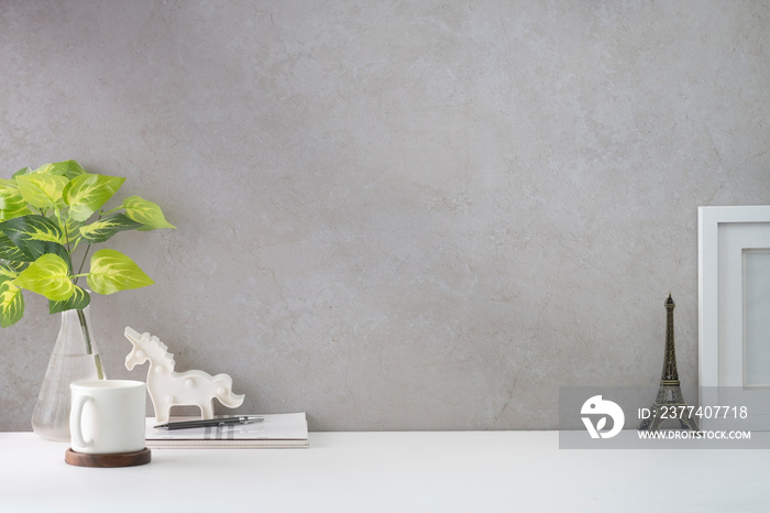 Comfortable workplace with picture frame, coffee, stationery and houseplant on white table..