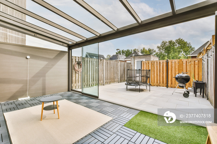 Neat paved patio with sitting area and small garden near wooden fence