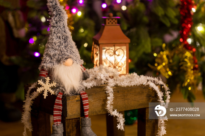 Christmas elf on a wooden bench and Christmas tree on background