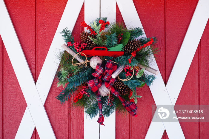 Christmas holiday pine wreath with pinecones and red bow on a red door