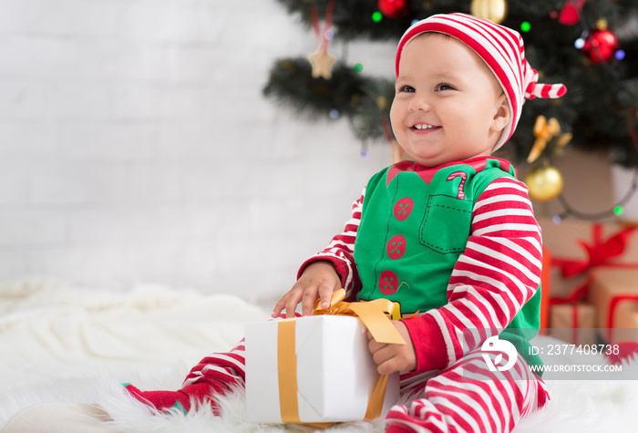 Adorable toddler enjoying Christmas time, playing with gift box