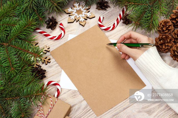 Famale hand writing a Christmas letter on wooden background