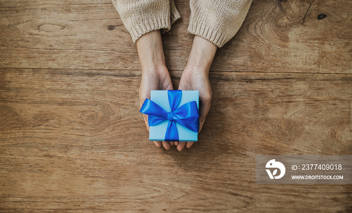 Woman holding beautiful gift box on wooden table background. Christmas, New year, Holiday concept