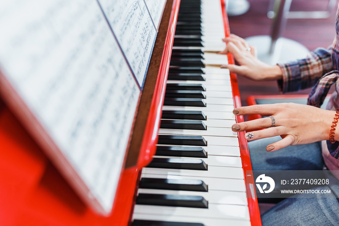 Close up of a womans hands playing a red piano - creative, and music concept