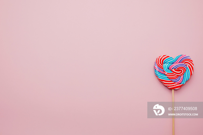 Heart shaped lollipop for Valentines Day and wooden toy with copy space pink background