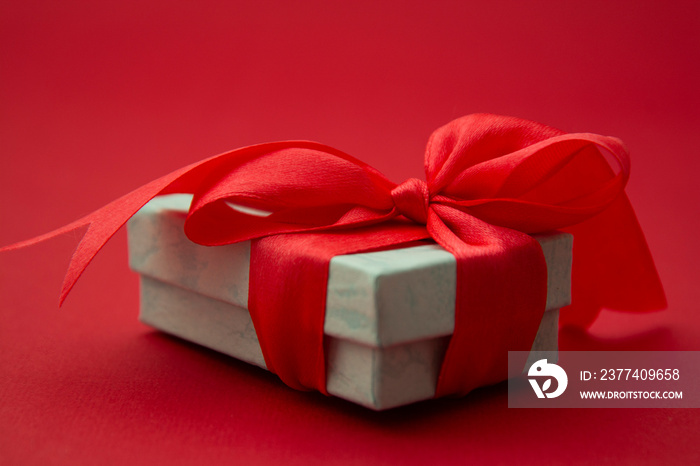 Close up gift box, birtday gift with red bow on red background. Love, Valentines Day, Mothers Day.