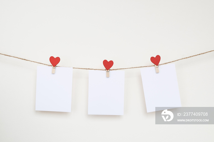 Three blank card on clothespins with hearts. Mockup for text on the beige background. For Valentines