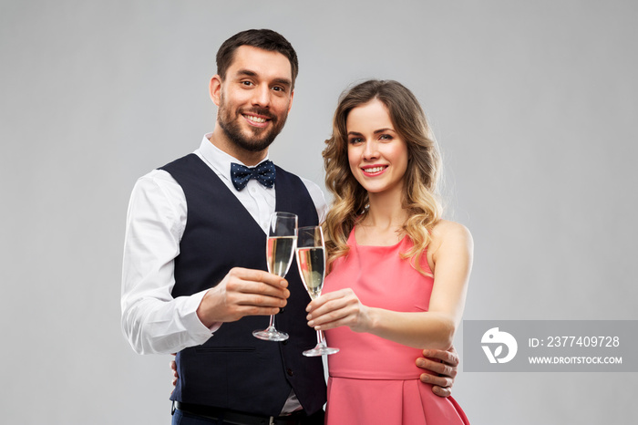 celebration and people concept - happy couple with champagne glasses toasting over grey background