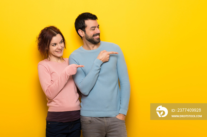 Couple in valentine day pointing finger to the side