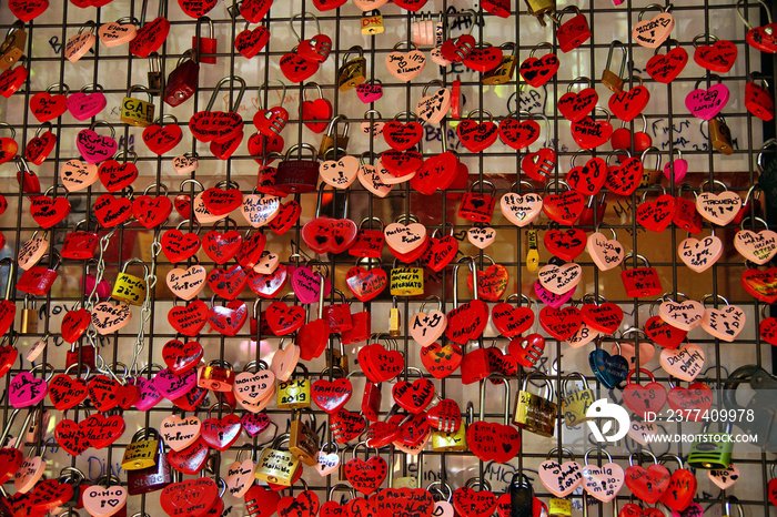 Locked locks of love and loyalty. Wall full of red and pink love locks shaped as hearts and classica