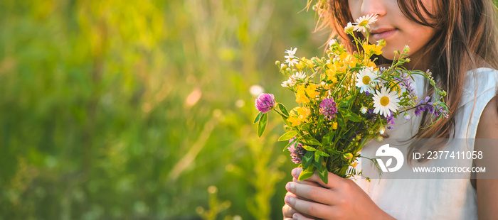 Child girl with wildflowers in summer. Selective focus.