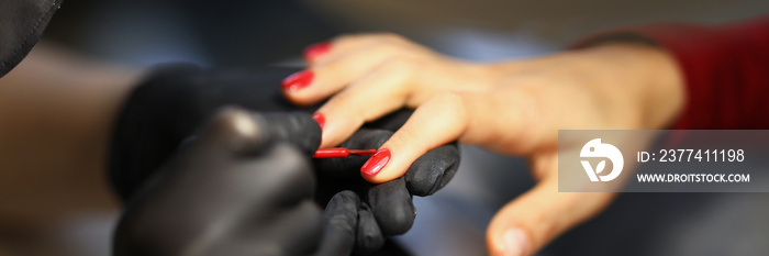 Manicurist painting woman nails with red varnish closeup