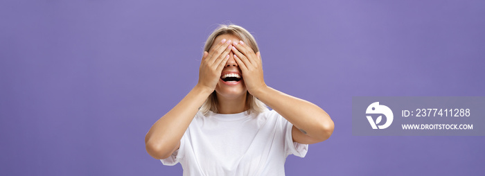 Can I look now. Portrait of excited pleased attractive tanned girlfriend in white t-shirt closing eyes and smiling broadly waiting for boyfriend bring surprising gift over purple background