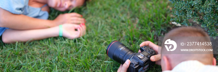 Man photographing young woman sleeping on grass